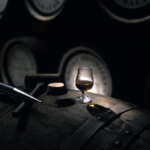 Whiskey in a glass on a barrel in a distillery