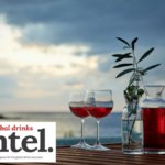 Two drinks and a bottle by the sea at sunset