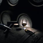 Whiskey in a glass on a barrel in a distillery