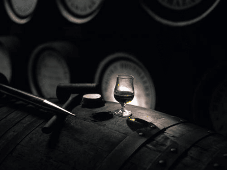 Whiskey in a glass on a barrel in a distillery