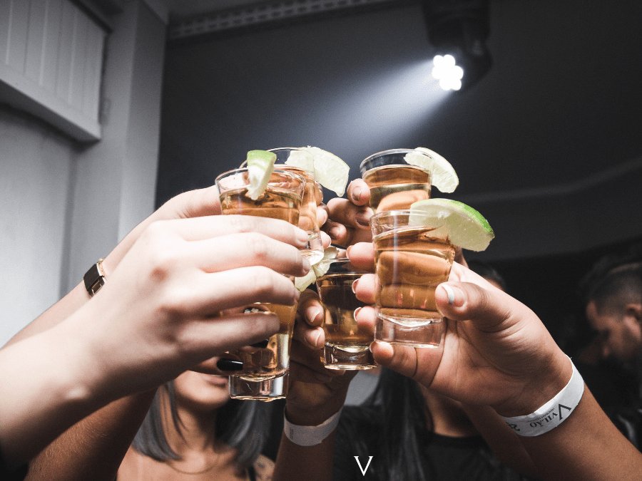 Consumers in a bar toasting with Tequila