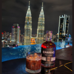 Kinahan's bottle with backdrop of Kuala Lumpur skyline at night
