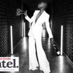 Woman in a wine cellar holding two empty wine glasses and a bottle of Ferrari Trento
