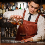 A bartender pouring a cocktail