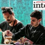 Two bartenders preparing cocktails behind a bar