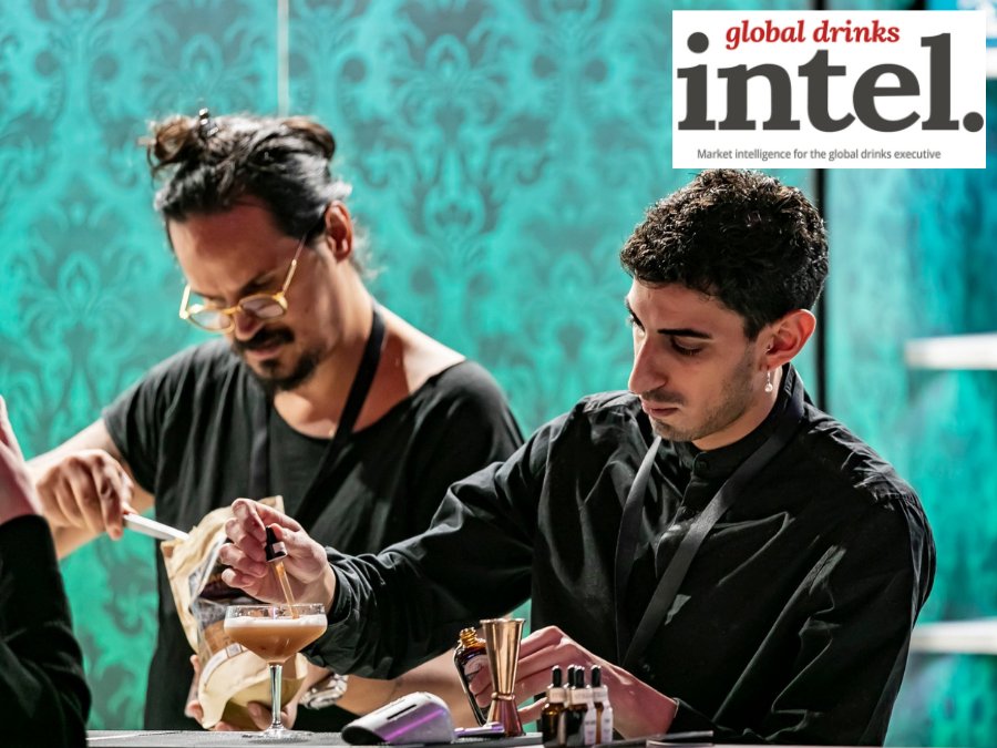 Two bartenders preparing cocktails behind a bar