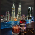 Kinahan's bottle with backdrop of Kuala Lumpur skyline at night