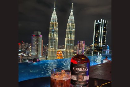 Kinahan's bottle with backdrop of Kuala Lumpur skyline at night