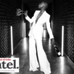 Woman in a wine cellar holding two empty wine glasses and a bottle of Ferrari Trento