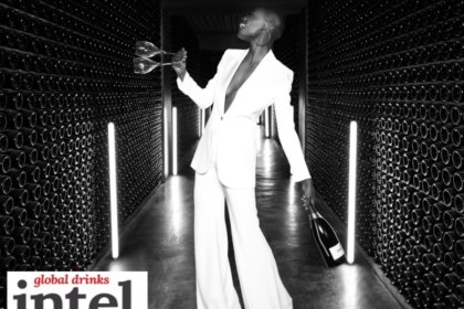 Woman in a wine cellar holding two empty wine glasses and a bottle of Ferrari Trento
