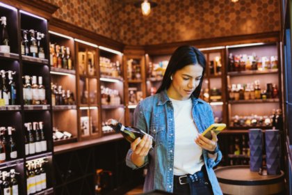 Woman looking at a phone in an alcohol off-premise outlet