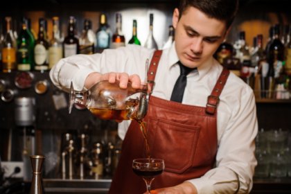 A bartender pouring a cocktail