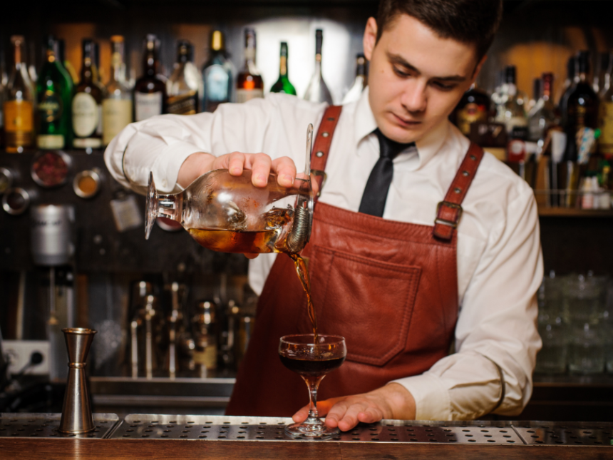 A bartender pouring a cocktail