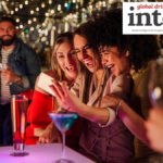 Three women at a bar with cocktails taking a selfie