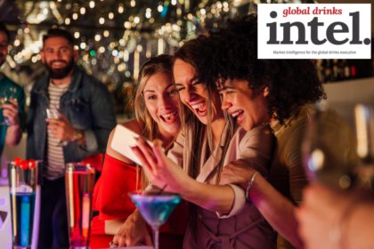 Three women at a bar with cocktails taking a selfie