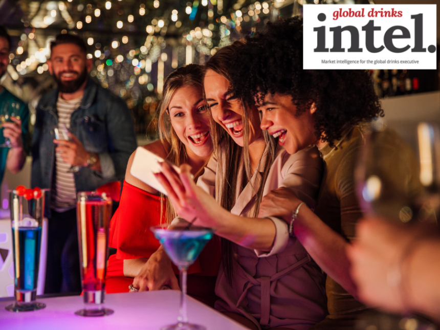 Three women at a bar with cocktails taking a selfie