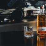 Bottle of Coachbuilt blended scotch whisky in front of a Williams Racing F1 car