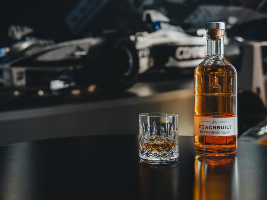 Bottle of Coachbuilt blended scotch whisky in front of a Williams Racing F1 car