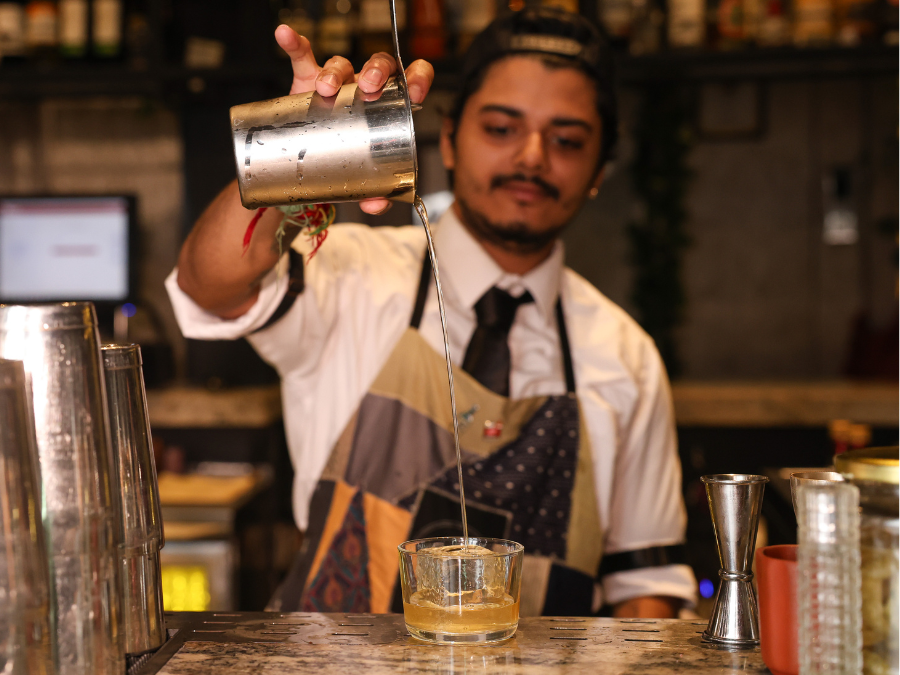 Bartender at PCO Mumbai pouring a cocktail