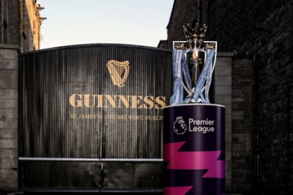The English Premier League trophy in front of a Guinness-branded gate