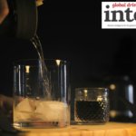 Brown spirit being poured into a glass with ice