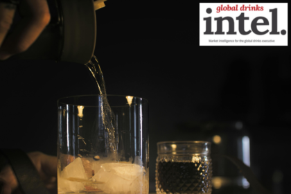 Brown spirit being poured into a glass with ice