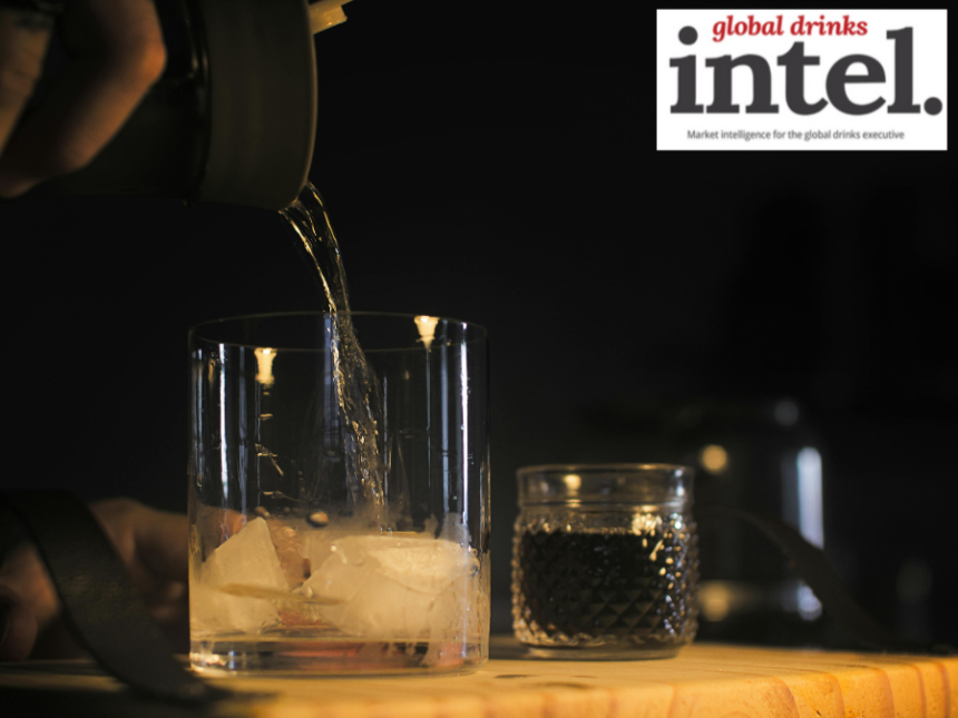 Brown spirit being poured into a glass with ice
