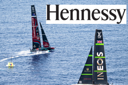 Two sailing boats competiting in the America's Cup and the Hennessy cognac logo