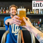 Bartender handing a drinker a full beer in a bar