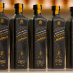 Line of five paper-based bottles of Johnnie Walker