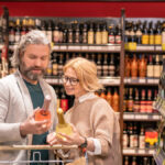 Two customers comparing bottles of wine in a supermarket