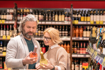Two customers comparing bottles of wine in a supermarket
