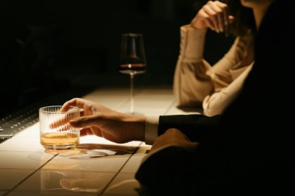 Person in a suit at a bar with an aged spirit in a glass