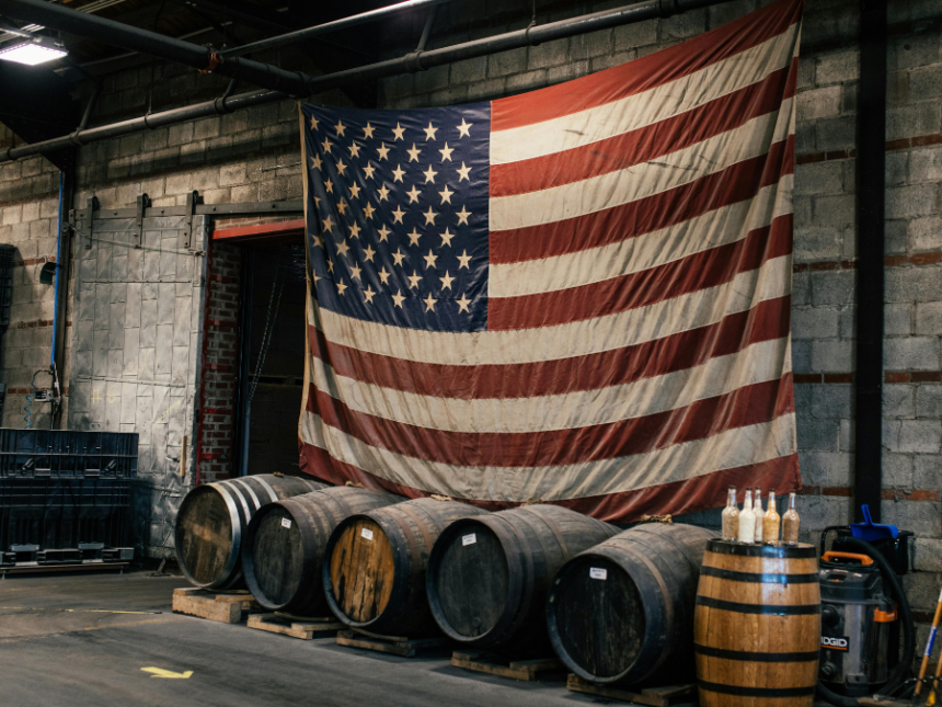 An American flag hanging above four barrels