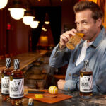 Two bottles of Bear Fight American whiskey on a bar with Gabriel Macht
