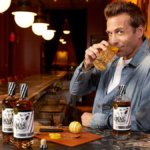 Two bottles of Bear Fight American whiskey on a bar with Gabriel Macht