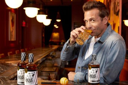 Two bottles of Bear Fight American whiskey on a bar with Gabriel Macht