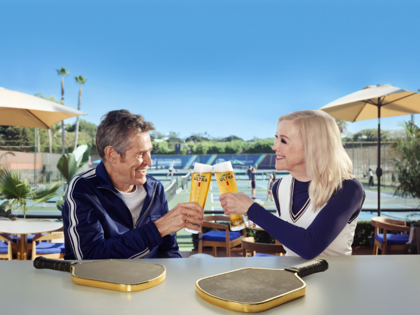 Willem Dafoe and Catherine O'Hara clinking Michelob Ultra beers