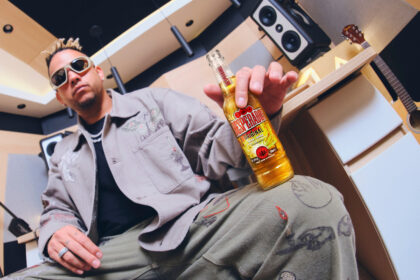 Ovy on the Drums holding a bottle of Desperados