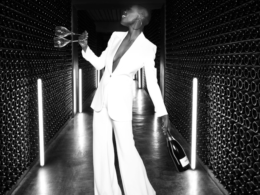 Woman in a wine cellar holding two glasses and a bottle of Ferrari Trento