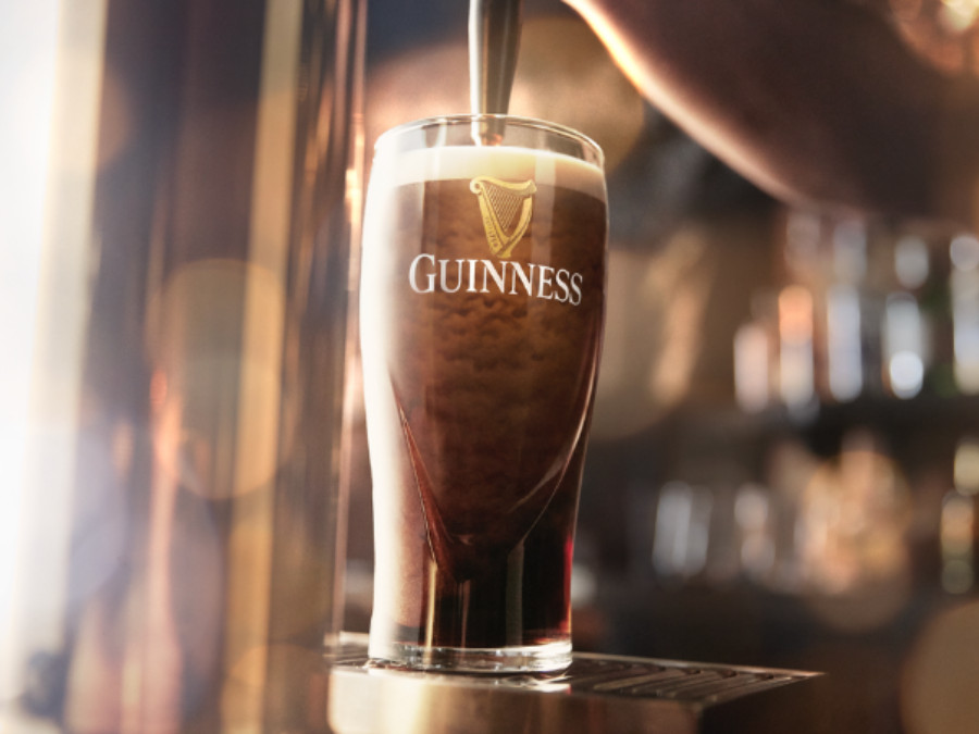 A pint of draught Guinness being poured into a branded glass