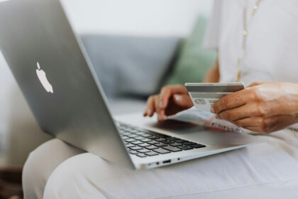 A consumer in front of a laptop holding a credit card