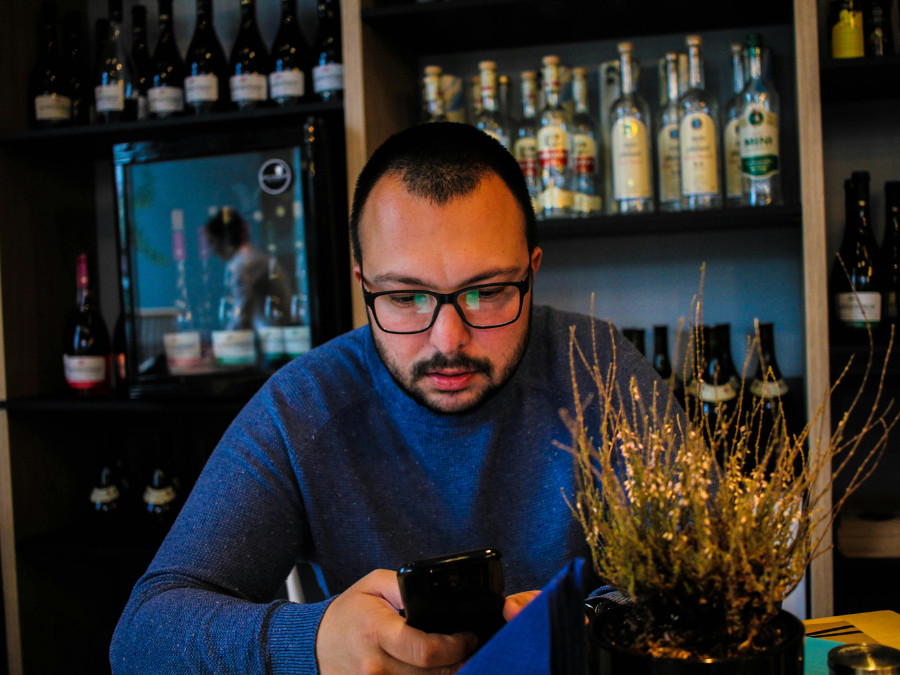 Man behind a bar looking at his phone