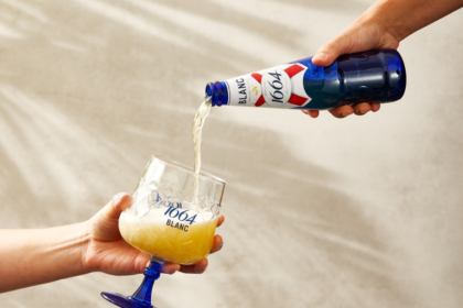 Bottle of 1664 Blanc pouring into stemmed glass