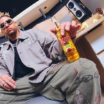 Ovy on the Drums holding a bottle of Desperados