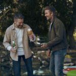 Matt Damon and David Beckham laughing with Stella Artois beer