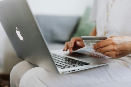 A consumer in front of a laptop holding a credit card