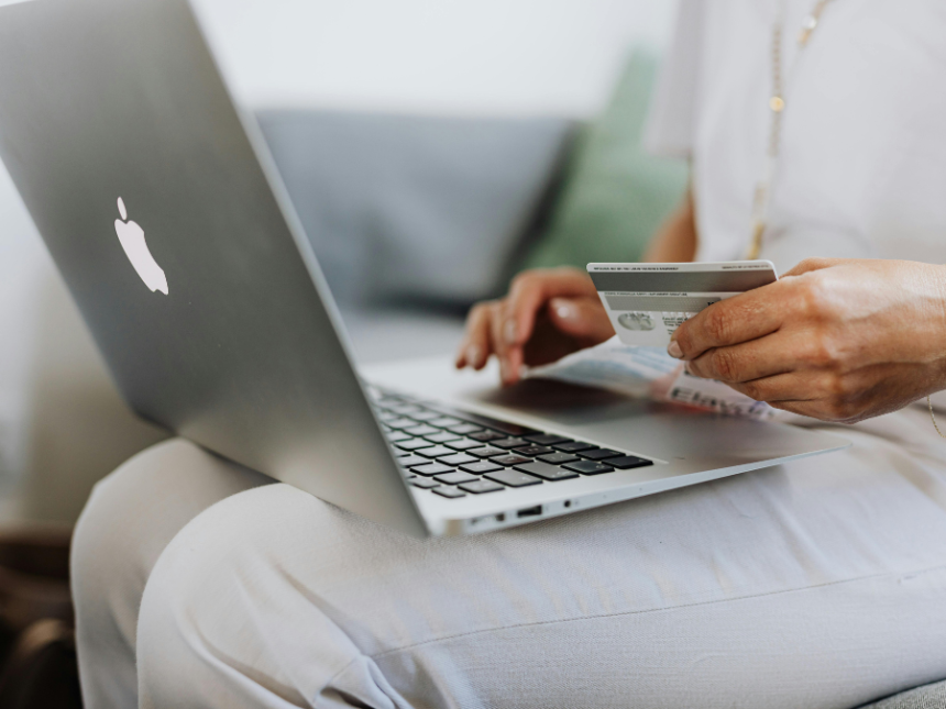 A consumer in front of a laptop holding a credit card