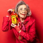 Elderly woman holding bottle of Fireball cinnamon whisky