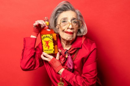 Elderly woman holding bottle of Fireball cinnamon whisky